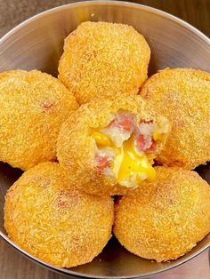 a metal bowl filled with fried food on top of a wooden table