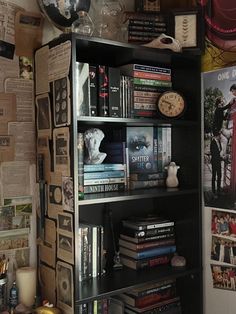 a bookshelf filled with lots of books next to a wall covered in posters