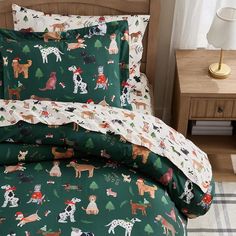 a bed covered in green and white sheets with christmas themed animals printed on the covers