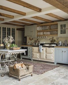 a dog laying in a basket on the floor next to a table with dishes on it