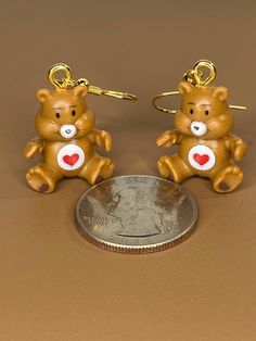 two brown teddy bears sitting on top of a table next to a coin and keychain