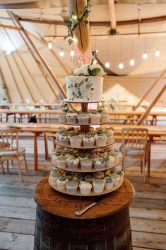 a wedding cake and cupcakes are stacked on top of each other in a tent