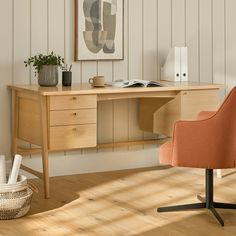 an office desk with a chair, potted plant and pictures on the wall