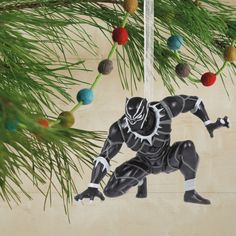 a black panther ornament hanging from a pine tree with christmas balls in the background