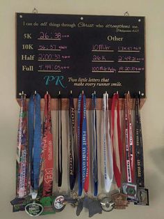 a chalkboard with medals hanging from it's sides on a wall next to other medals