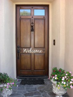 two planters with flowers sit in front of a door