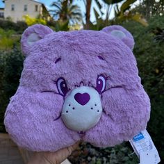 a purple teddy bear with big eyes on it's head is held up to the camera