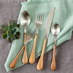 three forks, two spoons and one knife on a green napkin with succulents