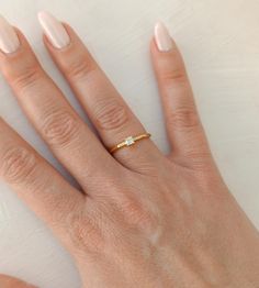 a woman's hand with a gold ring on top of her left hand and the middle finger