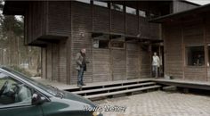 two men are standing in the doorway of a wooden building with steps leading up to it