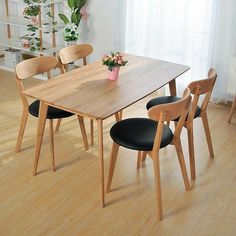 a wooden table with four chairs and a potted plant on top of the table