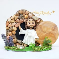 a figurine of jesus in front of a rock and stone house with plants