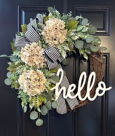 a wreath with the word hello is hanging on a black door and it says hello