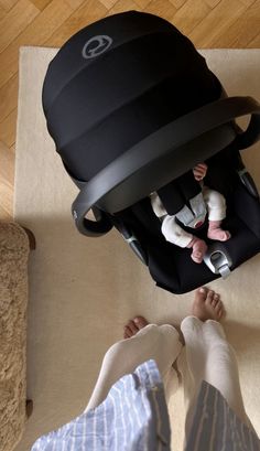 a baby sitting in a car seat next to a person's feet and legs