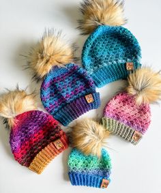 four knitted hats with multicolored fur pom poms on white background