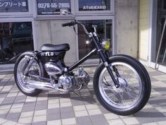 a black motorcycle parked in front of a building with no one sitting on the bike