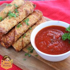 some food is on a wooden cutting board with a bowl of sauce and parsley