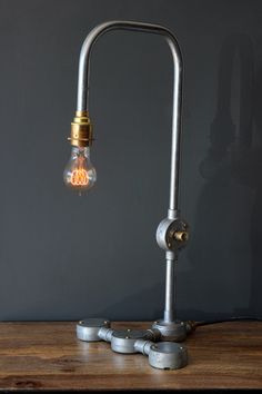 a lamp that is sitting on top of a wooden table in front of a gray wall