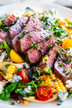 a white plate topped with steak, corn and salad next to a fork on a table