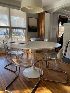 a white table and chairs in a room with wooden floors, windows, and a fireplace