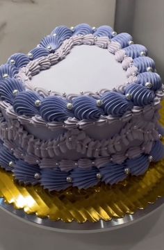 a large blue and white cake sitting on top of a metal platter with gold foil