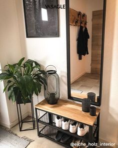 a mirror sitting on top of a wooden shelf next to a potted plant and shoe rack