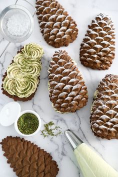 pine cone cookies with powdered sugar and sprinkles on a marble counter