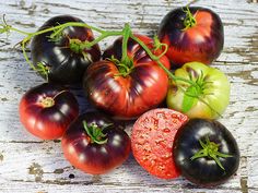 several different types of tomatoes on a wooden surface