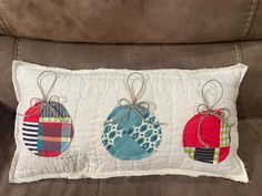 three handmade ornaments are hanging from the back of a couch pillow on top of a sofa