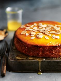 a cake with almonds on top is sitting on a plate next to utensils