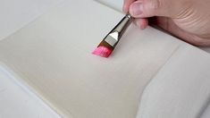 a person holding a paintbrush in their left hand and applying it to the fabric