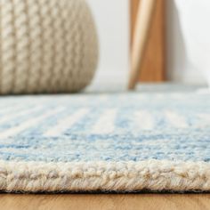 a close up view of a blue and white rug on a wooden floor with a chair in the background