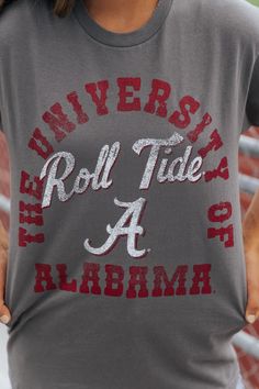 Roll Tide! For all you Alabama fans, this Graphic Tee is for you! Made of 100% cotton for a comfortable fit, this short sleeve tee features a relaxed fit and the iconic University of Alabama Roll Tide text. Perfect for any fan to show their support. Simply style it with your favorite jean shorts or denim jeans along with some sneakers or knee high boots for an elevated chic gameday outfit! Cotton Slogan T-shirt For Fan Gear, Collegiate T-shirt With Lettering For College, Casual T-shirt With Lettering For Fans, Casual Text Print T-shirt For Fan Gear, Casual T-shirt With Lettering For Game Day, Gray Cotton T-shirt With School Spirit, College Style Short Sleeve T-shirt For Game Day, Cotton Team Spirit T-shirt With Slogan, Sporty Short Sleeve T-shirt With Lettering