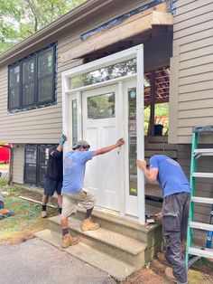 two men are painting the front door of a house