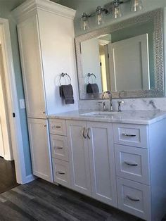 a bathroom with white cabinets and marble counter tops