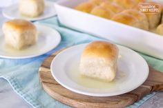 two plates with rolls on them next to a baking pan and blue towel in the background