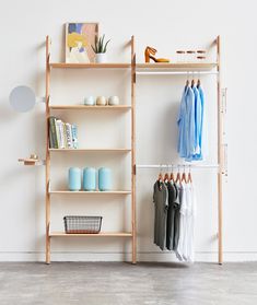 an open closet with clothes and shoes on shelves, next to a wall mounted mirror