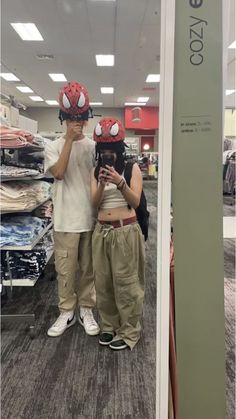 two people wearing helmets are taking a selfie in the mirror at a clothing store