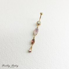 a gold plated belly ring with opal and pink stones on it's side