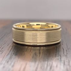 a gold wedding ring sitting on top of a wooden table