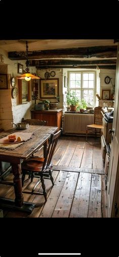 an old fashioned kitchen with wood flooring and wooden table in front of the window