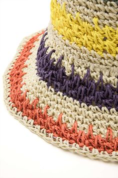 a multicolored crocheted hat is shown on a white surface with an orange, yellow, purple, and red stripe