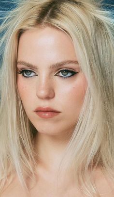 a woman with long blonde hair and blue eyes looks at the camera while posing for a photo