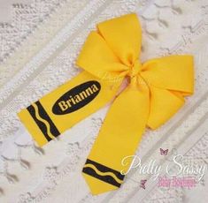 a yellow ribbon with the name brahma on it is laying on a white lace surface