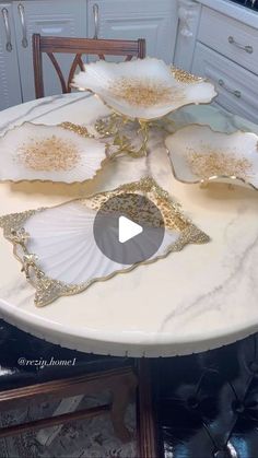 a white table topped with plates covered in gold leaf design on top of a kitchen counter