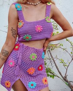 a woman wearing a purple crochet top and shorts with flowers on the bottom