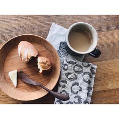 a wooden plate topped with pastries next to a cup of coffee on top of a table