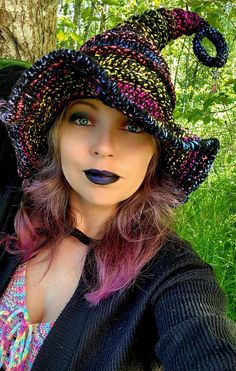 a woman with pink hair wearing a knitted hat and black lip gloss on her lips