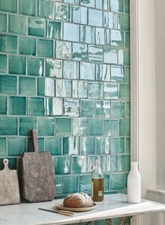 a kitchen counter topped with green tiles next to a white stove top oven and cutting board