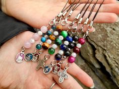 a person holding a bunch of beads in their hand with charms attached to the bead